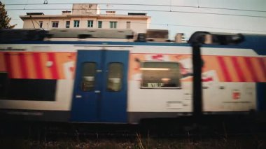 Cannes, Fransa - 21 Kasım 2025: Mavi bir banliyö treni bir konut binasının önünden hızla geçiyor ve durgun mimariye karşı güçlü hareket bulanıklığı yaratıyor