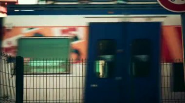 Cannes, Fransa - 22 Kasım 2025: Metal bir çitin arkasından geçen bulanık tren, güçlü grafik çizgileri olan soyut bir ulaşım sahnesi yaratıyor.