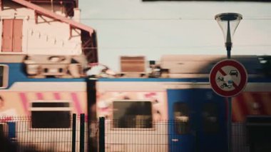 Hızlı giden tren gün ışığında yol tabelasının arkasından geçerken hareket bulanıklığıyla yakalanır.