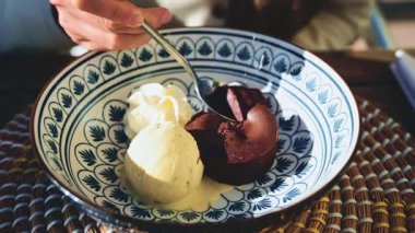 Vanilyalı dondurma ve çırpılmış kremayla servis edilen sıcak çikolata ile tabak çeviren bir kadın.