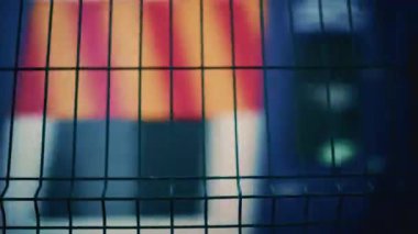 Metal bir çitin arkasından geçen bir tren. Renkli ve sığ bir odak noktası var.