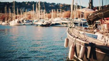 Yachts and sailing boats docked in a marina with sunlight reflecting on the water