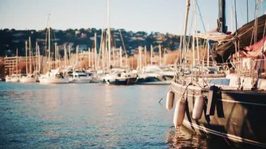 Yachts and sailing boats docked in a marina with sunlight reflecting on the water