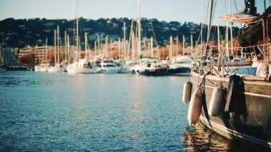 Yachts and sailing boats docked in a marina with sunlight reflecting on the water