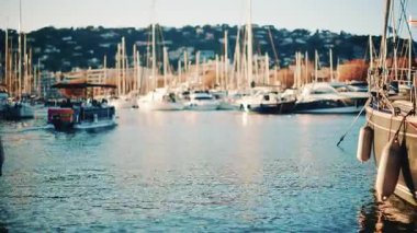 Yachts and sailing boats docked in a marina with sunlight reflecting on the water