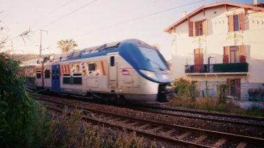 Golfe Juan, Fransa - 26 Kasım 2025: Hızlı hareket eden çift katlı bir tren, çevresindeki vahşi bitki örtüsüyle çevrili tren raylarından geçer