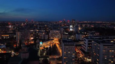 Varşova, Polonya - 30 Ekim 2025: Varşova 'nın yerleşim bölgelerinin hava aracı görüntüsü gece aydınlandı ve ufuk çizgisi uzaktan görülüyor