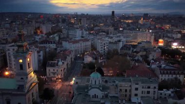 Belgrad 'ın hava aracı görüntüsü, yoğun kentsel ufuk çizgisini aydınlatan şehir ışıklarıyla geceye dönüşüyor. Yeni Belgrad 'ın modern kulelerine bakan eski bölgeden ele geçirildi