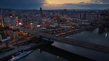 Belgrad, Sırbistan - 10 Kasım 2025: Belgrad 'daki köprülerin ve Sava Nehri' nin alacakaranlıktaki hava aracı görüntüsü, nehir kıyısındaki su ve trafik hareketinin ışık yansımalarını yakalıyor