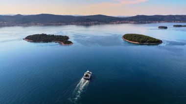 Pasman Kanalı 'nda küçük, yemyeşil adalarla çevrili bir feribot görüntüsü.