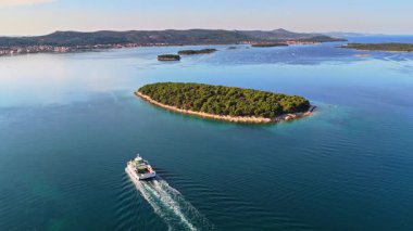Pasman Kanalı 'nda küçük, yemyeşil adalarla çevrili bir feribot görüntüsü.