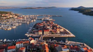 Tribunj 'un hava aracı görüntüsü, tekne dolu marinalar ve deniz boyunca yansıyan sıcak güneş ışığı. Hırvatistan