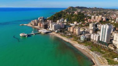 Arnavutluk 'un Durres kentindeki Adriyatik Denizi' nin turkuaz suları üzerinde uzanan ikonik dairesel Rotonda binasının hava aracı görüntüsü