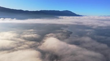 Bulutlar denizinin üzerinde yükselen Galiçya dağ sırtının hava aracı görüntüsü, aşağıdaki vadiyi kaplayan yumuşak sis tabakaları.
