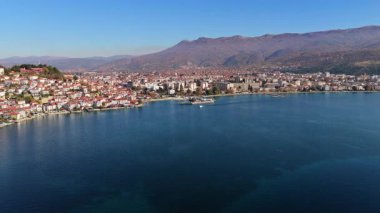 Ohri 'nin şehir merkezinin, sahil şeridinin ve etrafındaki tepelerin hava aracı görüntüsü parlak, berrak bir gökyüzünün altında.