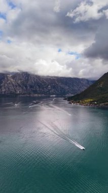 Hız teknelerinin hava aracı görüntüsü arka planda dağlarla birlikte körfezin sakin sularında beyaz izler bırakıyor. Dikey