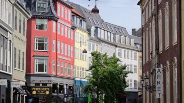 Copenhagen, Denmark - August 4, 2025: Row of traditional old street buildings with stores at street level. Pedestrians walking by and shopping