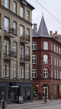 Kopenhag, Danimarka - 7 Ağustos 2025: Tarihi tuğla binalar ve bisiklet kullanan bir kişi