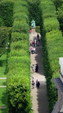 Kopenhag, Danimarka - 7 Ağustos 2025: Yeşil Kralın Bahçesi 'ndeki Hans Christian Andersen heykelinin yanından geçen turistler