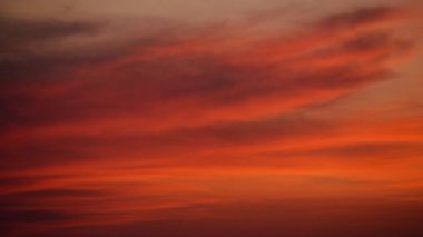 Gün batımı bulutları gökyüzünde ateş kırmızısı, turuncu ve altın renkler oluşturur.