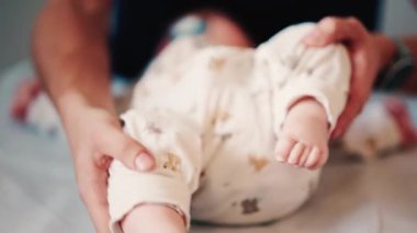 Bir bebeğin bacaklarını ve ayaklarını kapatırken, bakıcı bakımı sırasında ya da muayene sırasında bebeği nazikçe yeniden konumlandırır.