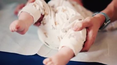 Bir bebeğin bacaklarını ve ayaklarını kapatırken, bakıcı bakımı sırasında ya da muayene sırasında bebeği nazikçe yeniden konumlandırır.