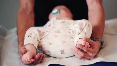 Bir bebeğin bacaklarını ve ayaklarını kapatırken, bakıcı bakımı sırasında ya da muayene sırasında bebeği nazikçe yeniden konumlandırır.