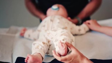 Bir bebeğin bacaklarını ve ayaklarını kapatırken, bakıcı bakımı sırasında ya da muayene sırasında bebeği nazikçe yeniden konumlandırır.