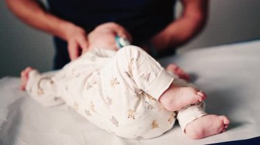 Bebek tıbbi bir masada sırt üstü yatarken bakıcılar rutin bir pediatrik değerlendirmeye hazırlanıyorlar.