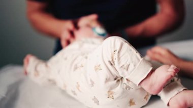 Bir bebeğin bacaklarını ve ayaklarını kapatırken, bakıcı bakımı sırasında ya da muayene sırasında bebeği nazikçe yeniden konumlandırır.