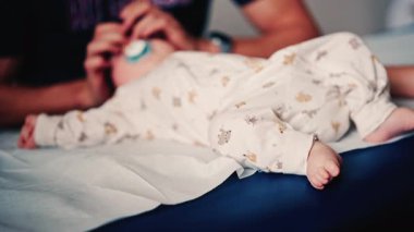 Bebek, pediatrik seans sırasında bir bakıcı tarafından nazikçe kucaklandı.