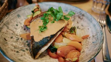 Restoran ortamında sebze ve kremalı sosla servis edilen balık filetosunu kapat.
