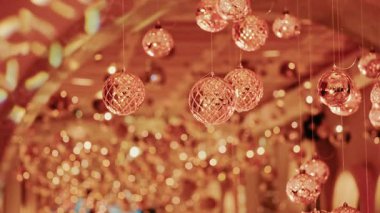 Asılı Noel süsleri, altın bokeh ışıklarının yumuşak arka planında parlıyor.