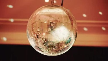 Ilık bir iç mekanda ışık desenlerini yansıtan parlak disko topu.