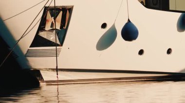 Fransız Rivierası 'ndaki bir marinada çamurlukları ve demirleme halatları olan beyaz bir yatın gövdesini kapatın.