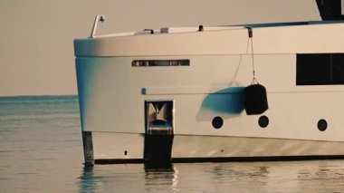 Üzerinde asılı siyah çamurluk ve su hattı olan lüks bir yatın gövdesine yakın plan.
