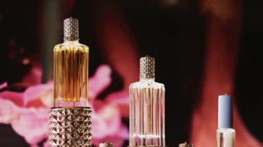 Altın ve kristal detaylarla süslü zarif cam parfüm şişeleri, yumuşak ışıklandırma ve çiçeklerle biçimlendirilmiş.