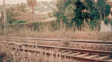 Arka planda endüstriyel dokular ve şehir unsurları ile kentsel bir ortamda demiryolu boyunca hareket eden bir yolcu treninin yan görüntüsü