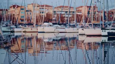 Tekneler, arkalarında renkli binalar bulunan bir rıhtım boyunca dizilmiş.