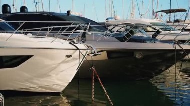 Sakin su yansımaları ve berrak gün ışığıyla marinaya bağlı modern motor yatları.