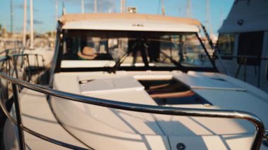 Limana demirlemiş bir teknenin kokpitine yerleştirilmiş hasır şapkayı kapat, marina detayları arka planda yavaşça bulanıklaşsın.