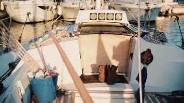 Yelkenli kokpitinin detaylı görüntüsü. İpler, botlar ve sıcak öğleden sonra ışıklarıyla aydınlatılan günlük yelkencilik ekipmanları.