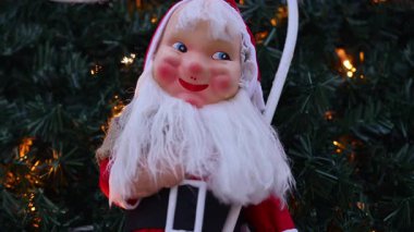 Noel Baba dekorasyonu, Noel ağacı dalları ve sıcak tatil ışıklarıyla çerçevelenmiş açık havada sergilendi.