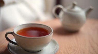 Ahşap bir masada, aynı tabağa konmuş sıcak çayla dolu seramik fincanı kapat.