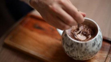 Kakao tozuyla kaplı seramik bardağı kapat, ahşap tepsiye koy.