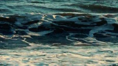 Okyanus dalgaları kıyı şeridine yaklaşırken kırılıp köpürüyor.