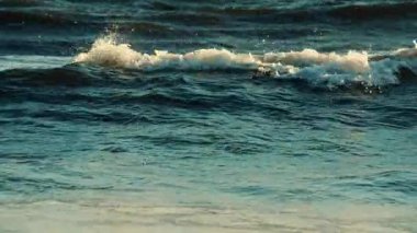 Okyanus dalgaları kıyı şeridine yaklaşırken kırılıp köpürüyor.