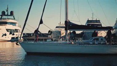 Cannes, Fransa - 12 Aralık 2025: Yelkenli yat limanında gündüz vakti güvertede birkaç kişi dururken hareket ediyor