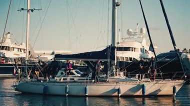 Cannes, Fransa - 12 Aralık 2025: Yelkenli yat limanında gündüz vakti güvertede birkaç kişi dururken hareket ediyor