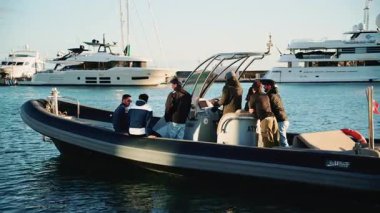 Cannes, Fransa - 23 Aralık 2025: Küçük bir grup insan, arka planda demir atmış büyük bir yatla limanın yakınındaki şişme bir teknede oturuyordu.